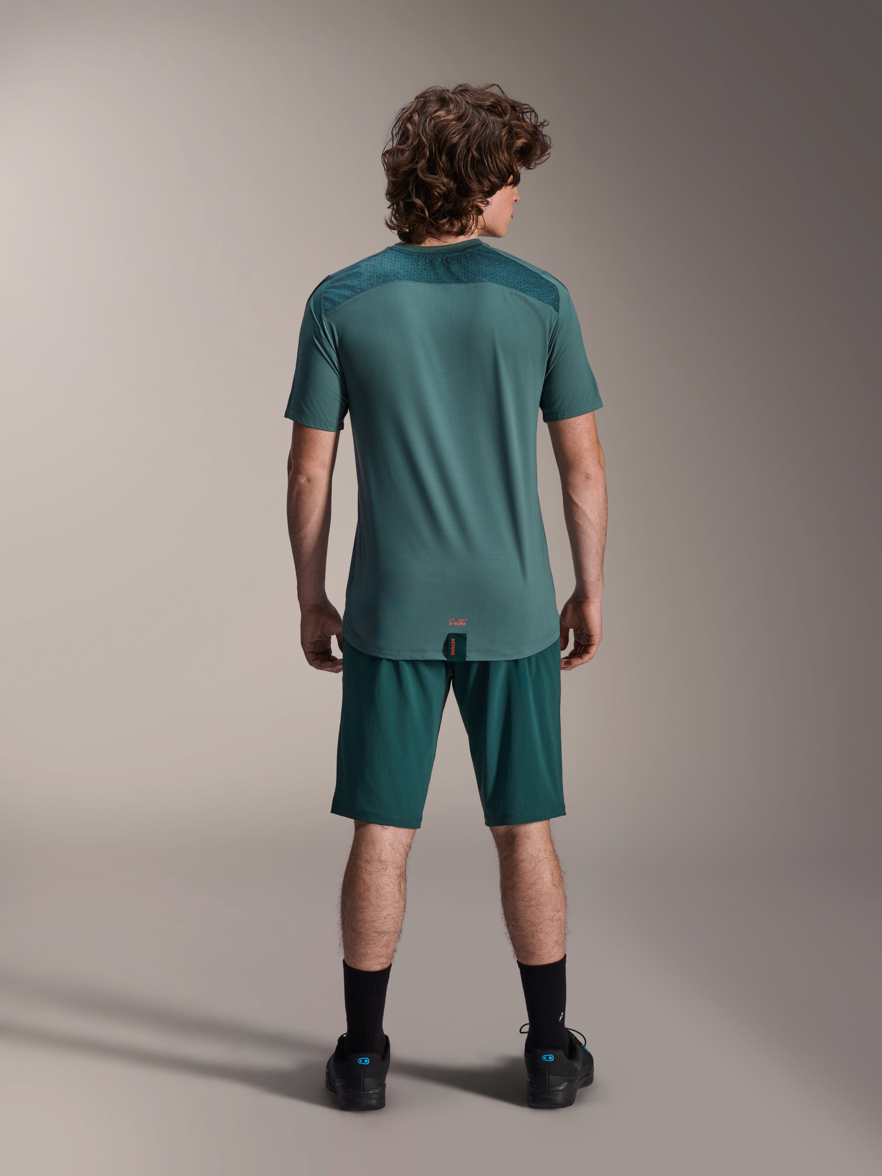 Alpinestars A-Dura Shorts en A-Dura Lipan SS Jersey, Dark Pine groen, achteraanzicht op een model, performance mountainbike-kleding bestaande uit een shirt met korte mouwen en bijpassende shorts, off-road fietsoutfit