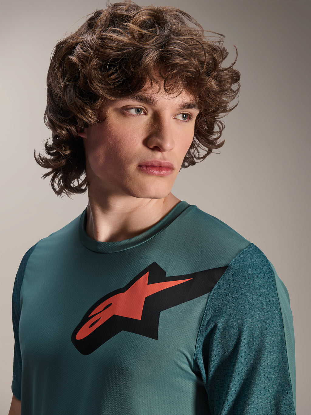 Alpinestars A-Dura Lipan Jersey, MTB-jersey met korte mouwen, Silver Pine, met een opvallend rood en zwart Astars-logo op de borst, getextureerde jacquard mouwen, close-up portret van een model dat technische wielerkleding draagt