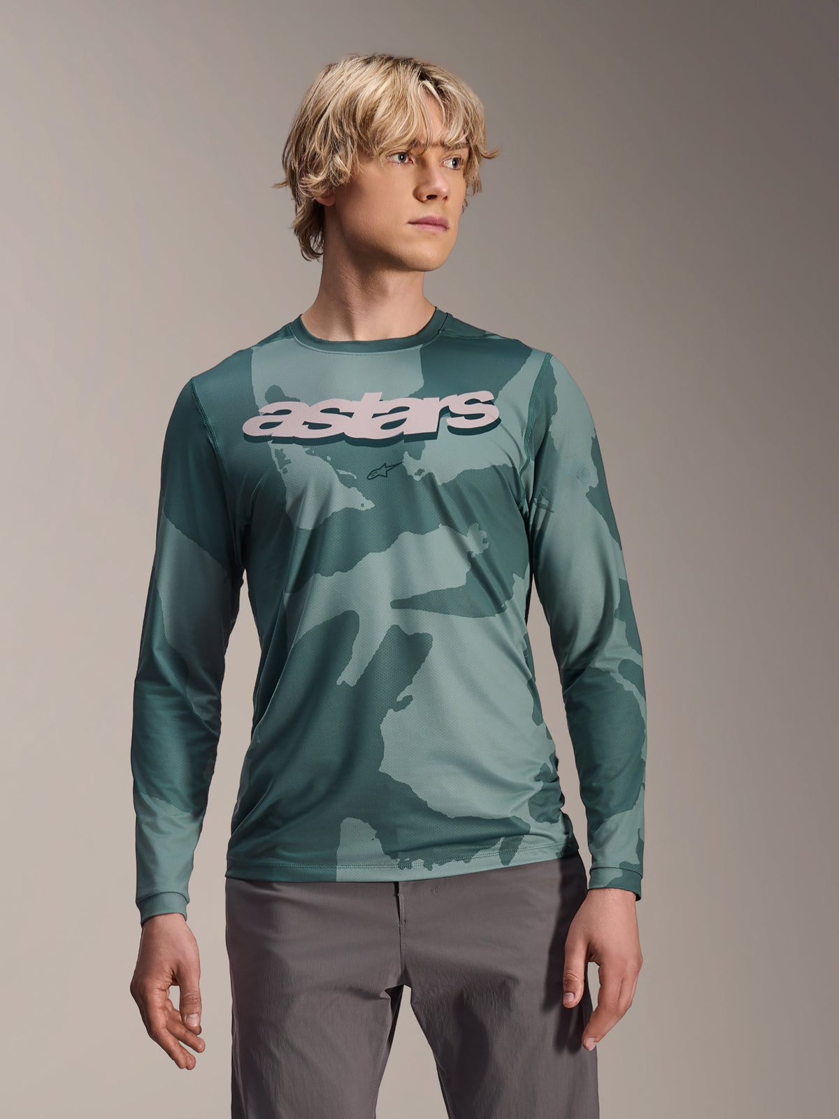 Alpinestars A-Dura Hollow Camo Langarmtrikot, MTB-Jersey, Silver Pine Camo grünes Tarnmuster, großes hellgraues astars-Logo auf der Brust, kombiniert mit grauer Hose, leistungsstarke Mountainbike-Bekleidung