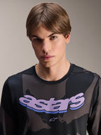 Maillot Alpinestars A-Dura Hollow Camo à manches longues, camouflage noir avec graphique 'astars' violet sur la poitrine, photo en studio d'un mannequin portant une tenue de VTT, style de vélo de montagne décontracté et technique