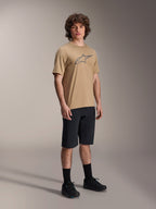 Maillot à manches courtes Alpinestars A-Dura Astar, marron clair, avec un grand logo Astar gris foncé sur la poitrine, porté par un mannequin avec un short de VTT noir, des chaussettes noires et des chaussures noires, tenue de VTT performante et décontractée dans un studio
