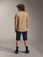Mannelijk model van achteren gezien in Alpinestars A-Dura Liner Shorts in het zwart en een beige jersey met korte mouwen, gecombineerd met zwarte sokken en schoenen, duurzame mountainbikekleding voor off-road fietsen.