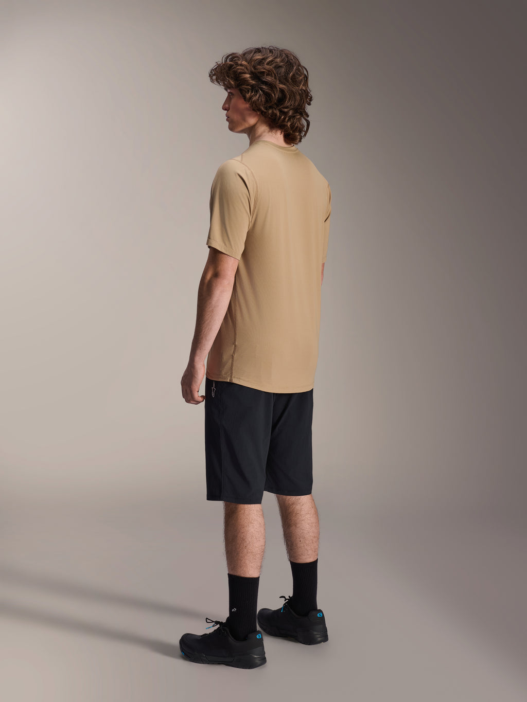 Short Alpinestars A-Dura, short de VTT, noir, associé à un maillot à manches courtes A-Dura beige et des chaussures de vélo noires, présentant une coupe régulière et une construction durable pour le cyclisme tout-terrain, vue latérale arrière