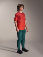 Model trägt Alpinestars A-Dura Hose in Dark Pine, kombiniert mit einem roten A-Dura Rise Kurzarmtrikot und schwarzen MTB-Schuhen, sportliche Mountainbike-Bekleidung in einer Studio-Umgebung