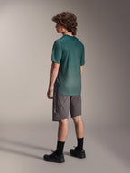 Alpinestars A-Dura Rise Jersey, MTB-shirt met korte mouwen, Silver Pine groen, gedragen met grijze short en zwarte schoenen, achteraanzicht met verlengde achterkant en regular fit, lichtgewicht vochtafvoerende stof voor trailrijden
