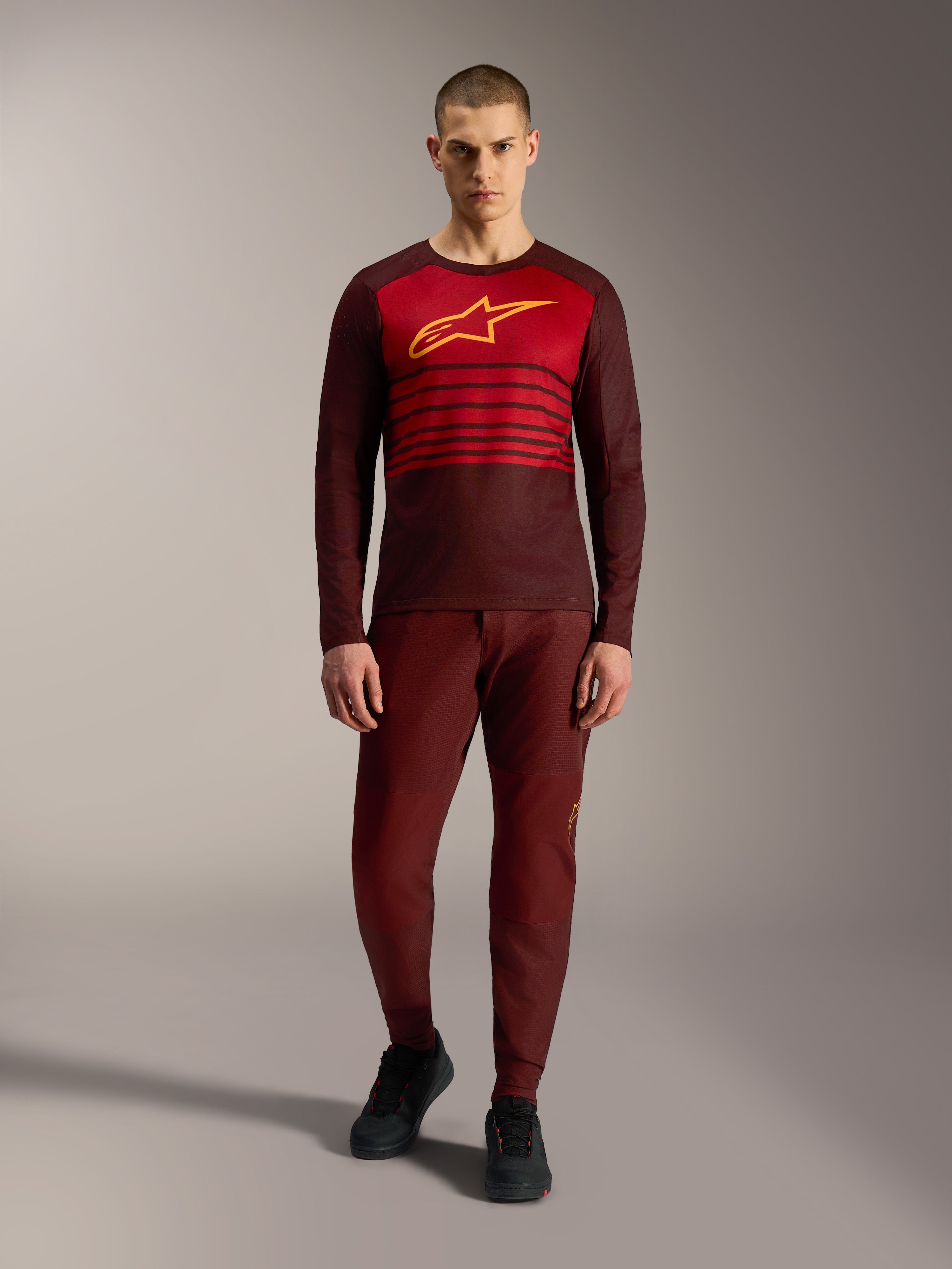 Alpinestars A-Dura Elite 2.0 MTB-trui in bordeauxrood met lange mouwen, geel borstlogo en rode strepen op de borst.