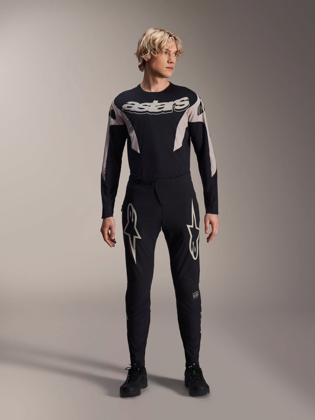 Maillot Alpinestars A-Supra Melt, maillot de VTT à manches longues, noir avec marquage Astars blanc sur la poitrine, porté avec un pantalon de VTT noir assorti orné de logos en étoile, équipement de cyclisme haute performance