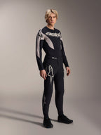Mannequin homme portant le pantalon Alpinestars A-Supra Melt et le maillot à manches longues assorti, noir avec motifs incurvés gris clair, avec logos Astars blancs sur les jambes et logo textuel sur la poitrine, tenue de course de VTT professionnelle.