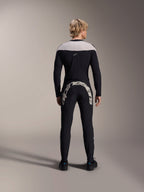 Alpinestars A-Supra Melt Pants, noir, vue arrière montrant le grand logo Alpinestars blanc sur l'empiècement arrière, associé à un maillot à manches longues assorti et des chaussures de cyclisme noires, équipement de VTT haute performance pour la pratique tout-terrain