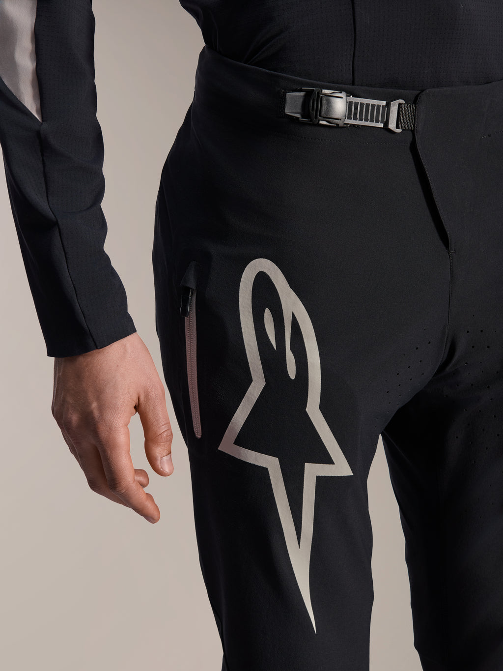 Pantalon Alpinestars A-Supra Melt, pantalon de VTT, noir, avec un grand logo Astar blanc sur la cuisse, fermeture de la taille à cliquet réglable et poche latérale zippée, vue détaillée d'un équipement technique de performance pour le VTT