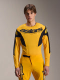 Maillot Alpinestars Édition Limitée A-Supra Melt Gold, maillot de VTT à manches longues, jaune foncé avec des accents noirs, porté par un mannequin avec un pantalon assorti, arborant un grand logo « astars » noir sur la poitrine et un design de performance athlétique