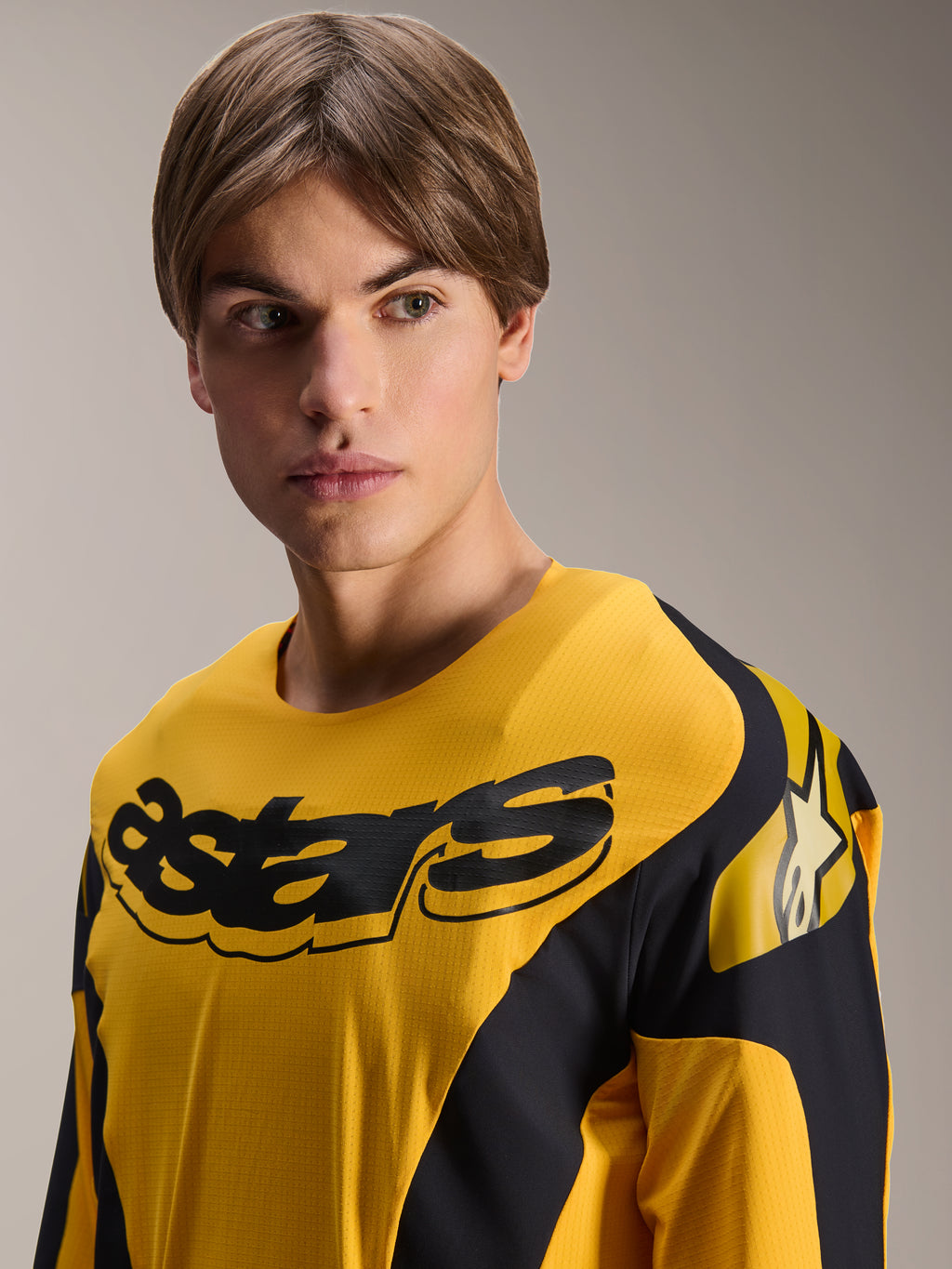 Maillot Alpinestars Limited Edition A-Supra Melt Gold, maillot de VTT à manches longues, jaune foncé avec graphismes noirs inspirés de la course, comprenant le lettrage 'astars' noir sur la poitrine et le logo étoilé sur l'épaule, porté par un modèle masculin