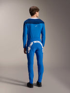 Modèle masculin vu de dos portant le maillot à manches longues Alpinestars A-Supra Melt en bleu, associé à un pantalon de performance bleu assorti arborant un grand logo textuel Alpinestars blanc dans le dos, tenue de course VTT complète.