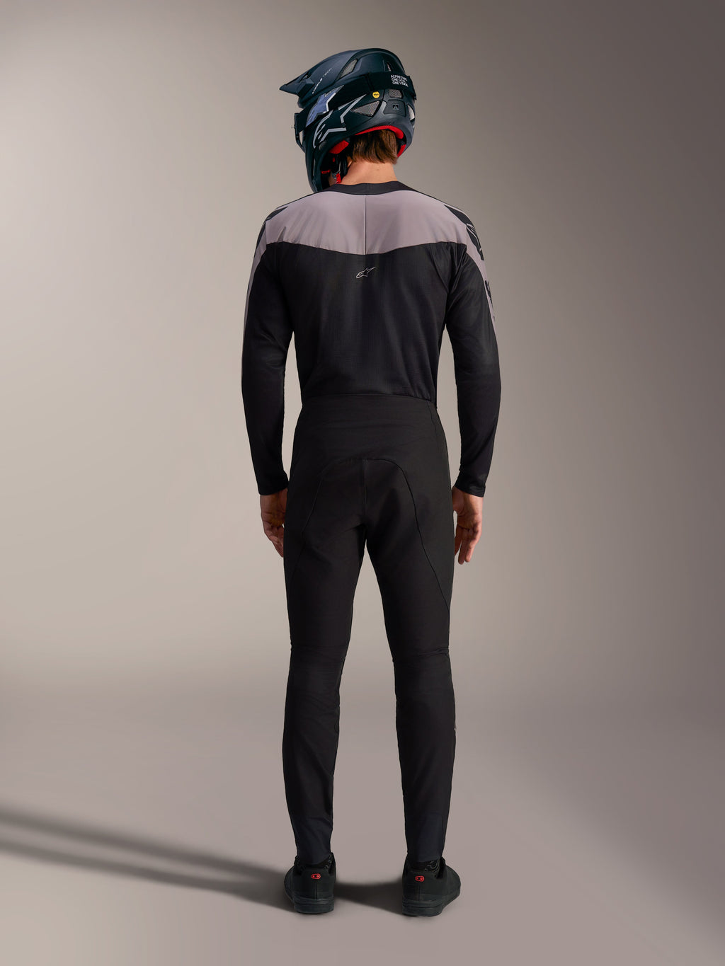 Zwarte Alpinestars A-Supra Elite MTB-kit met performance broek, jersey en full-face helm, achteraanzicht.