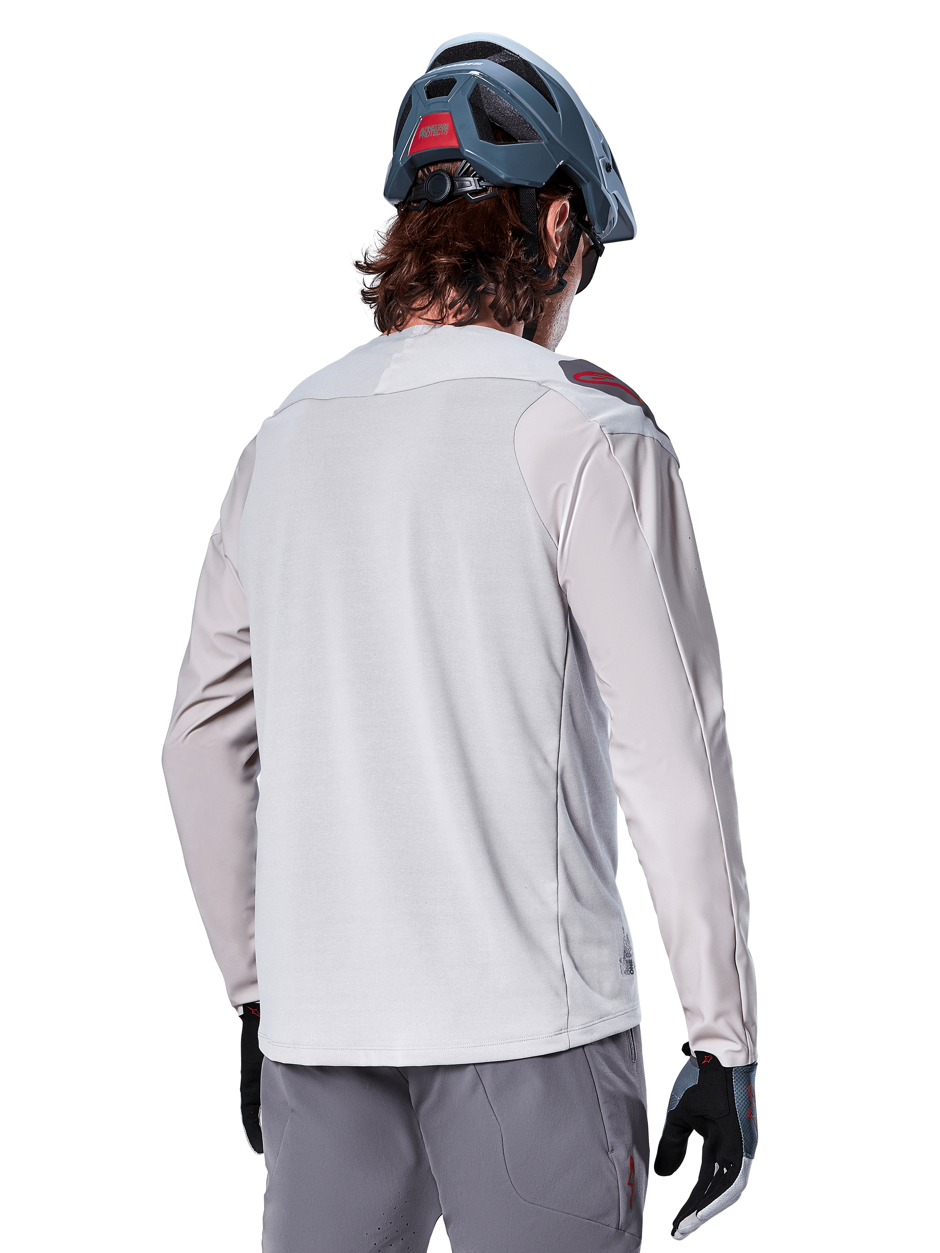 Maillot à manches longues Alpinestars A-Aria Polartec Switch, gris clair, vue de dos sur un cycliste, porté avec un casque de VTT bleu et un pantalon gris, vêtement de VTT performant pour les sentiers tout-terrain