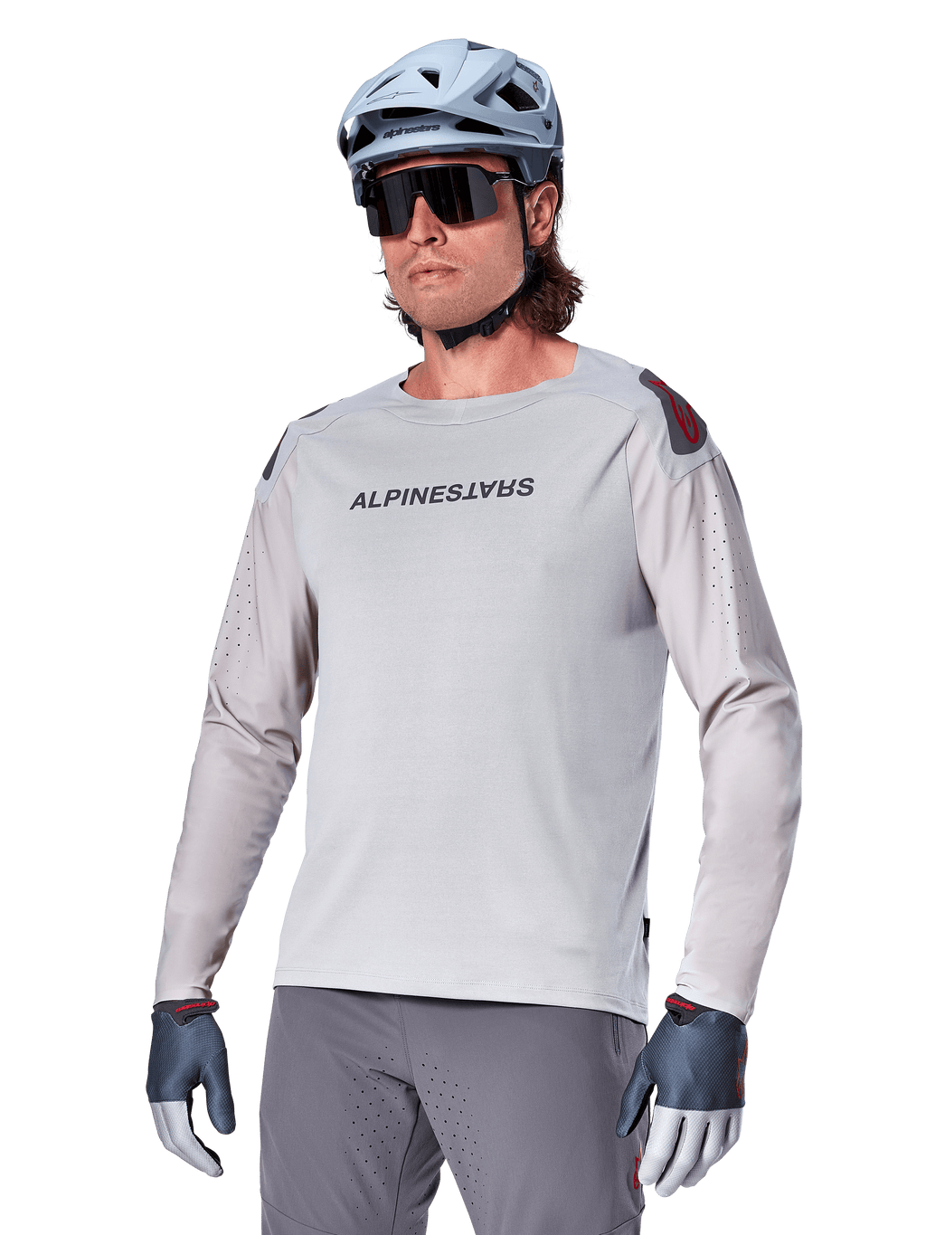 Alpinestars A-Aria Polartec Switch Jersey à manches longues, maillot de cyclisme gris clair avec logo noir sur la poitrine et accent rouge sur l'épaule, manches perforées au laser pour la ventilation, porté avec un casque bleu clair, des lunettes de soleil et un pantalon gris, tenue de VTT haute performance pour le trail