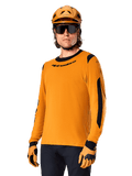 Alpinestars A-Dura Dri Wool Jersey met lange mouwen, MTB mountainbike-shirt, donkergoud en zwart, voorzien van een vochtafvoerende merinowolmix en mesh-panelen, fietser met bijpassende helm, zonnebril en handschoenen