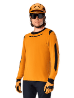 Alpinestars A-Dura Dri Wool Jersey met lange mouwen, MTB mountainbike-shirt, donkergoud en zwart, voorzien van een vochtafvoerende merinowolmix en mesh-panelen, fietser met bijpassende helm, zonnebril en handschoenen