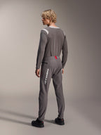 Model van achteren gezien in Alpinestars MTB-kleding, grijze A-Dura Dri Wool Jersey met lange mouwen, donkergrijze A-Dura Elite Pants met witte verticale branding en rood detail op de tailleband, gecoördineerde fietsoutfit voor mountainbiken