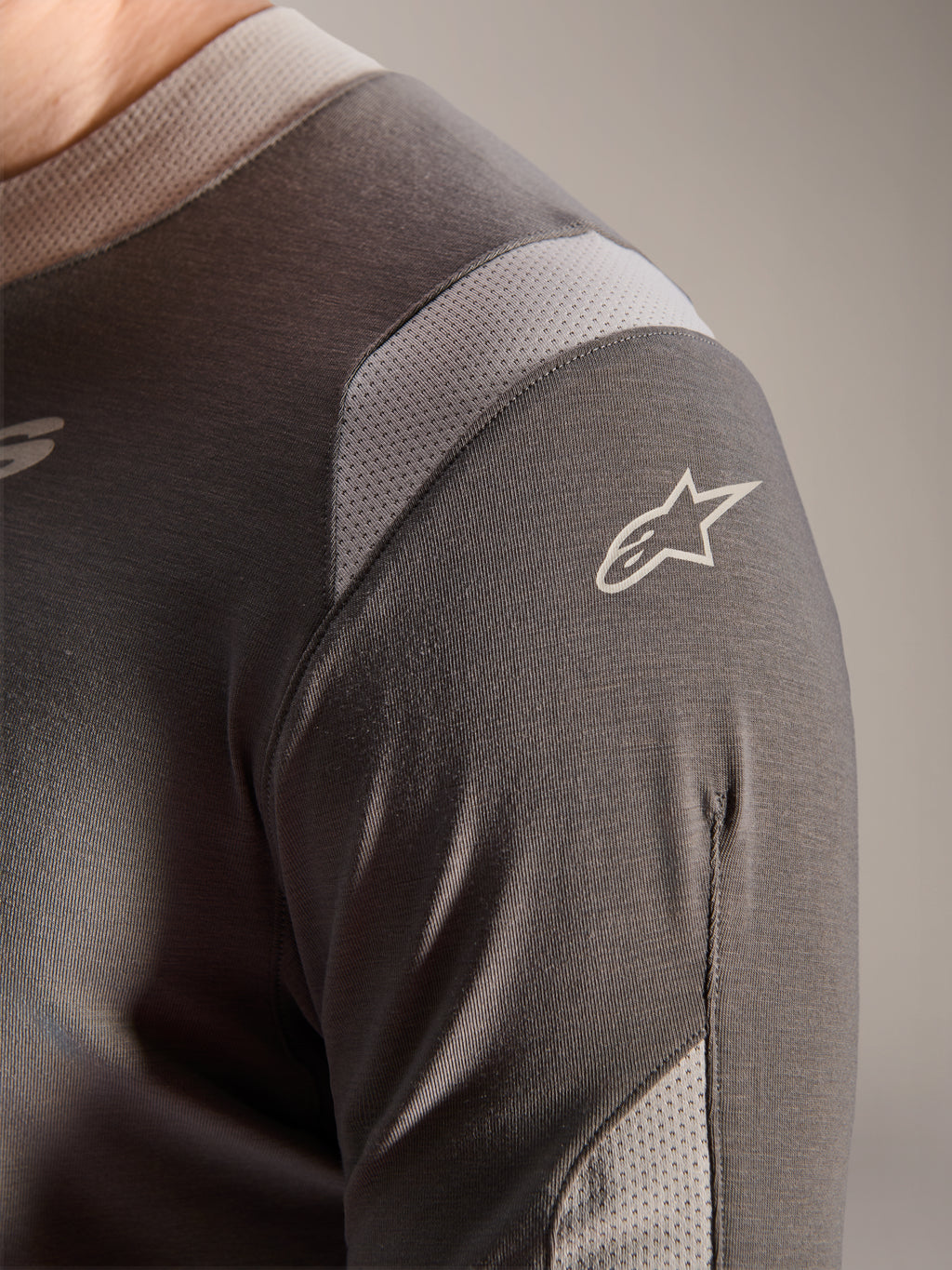 Alpinestars A-Dura Dri Wool Jersey - Lange Mouwen, donkergrijs, detailopname van de schouder en mouw met lichtgrijze mesh ventilatiepanelen en het witte Astars-logo op de technische drirelease-stof.