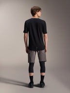 Alpinestars A-Dura Elite Shorts, dunkelgraue Mountainbike-Shorts, Rückansicht, getragen mit einem schwarzen Kurzarmtrikot, Knieschützern und schwarzen Socken, technische Fahrradausrüstung für den Offroad-Einsatz
