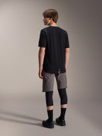 Alpinestars A-Dura Dri Wool Kurzarmtrikot, Schwarz, Rückansicht am Modell, getragen mit grauen Mountainbike-Shorts und schwarzen Knieprotektoren, mit verlängertem Rückensaum und dezentem Logo, technische MTB-Bekleidung