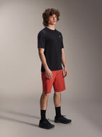 Männliches Model in Alpinestars A-Dura Elite Shorts in Dark Orange und A-Dura Dri Wool Kurzarm-Trikot in Schwarz, Mountainbike-Performance-Ausrüstung, kombiniert mit schwarzen Socken und Schuhen, sportliches Design für Offroad-Radsport