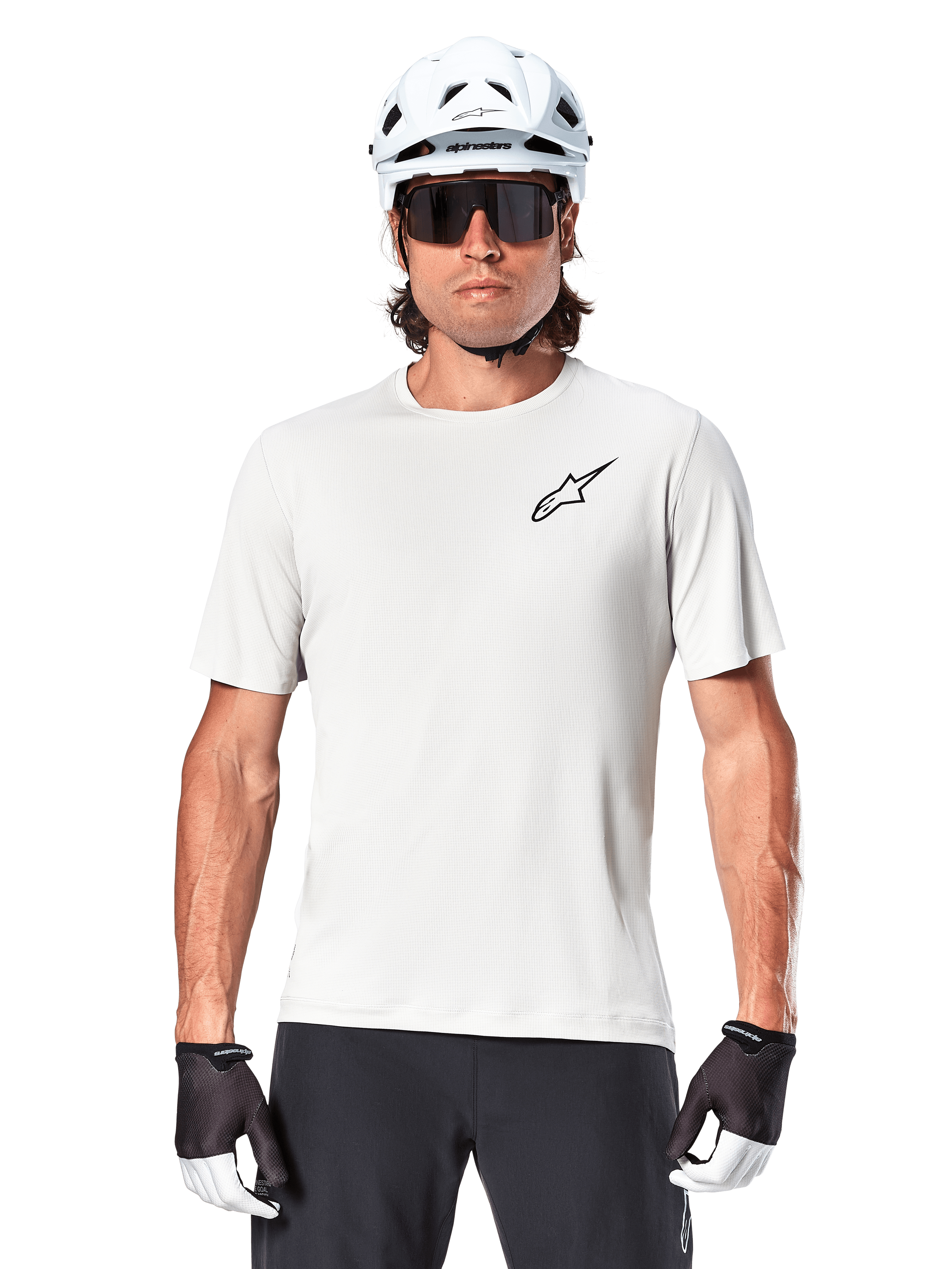 Cycliste portant le maillot à manches courtes Alpinestars A-Aria Astar, White Dove avec petit logo Astar noir sur la poitrine, casque de cyclisme blanc, lunettes de soleil noires et gants noirs et blancs, équipement VTT performant pour la conduite tout-terrain