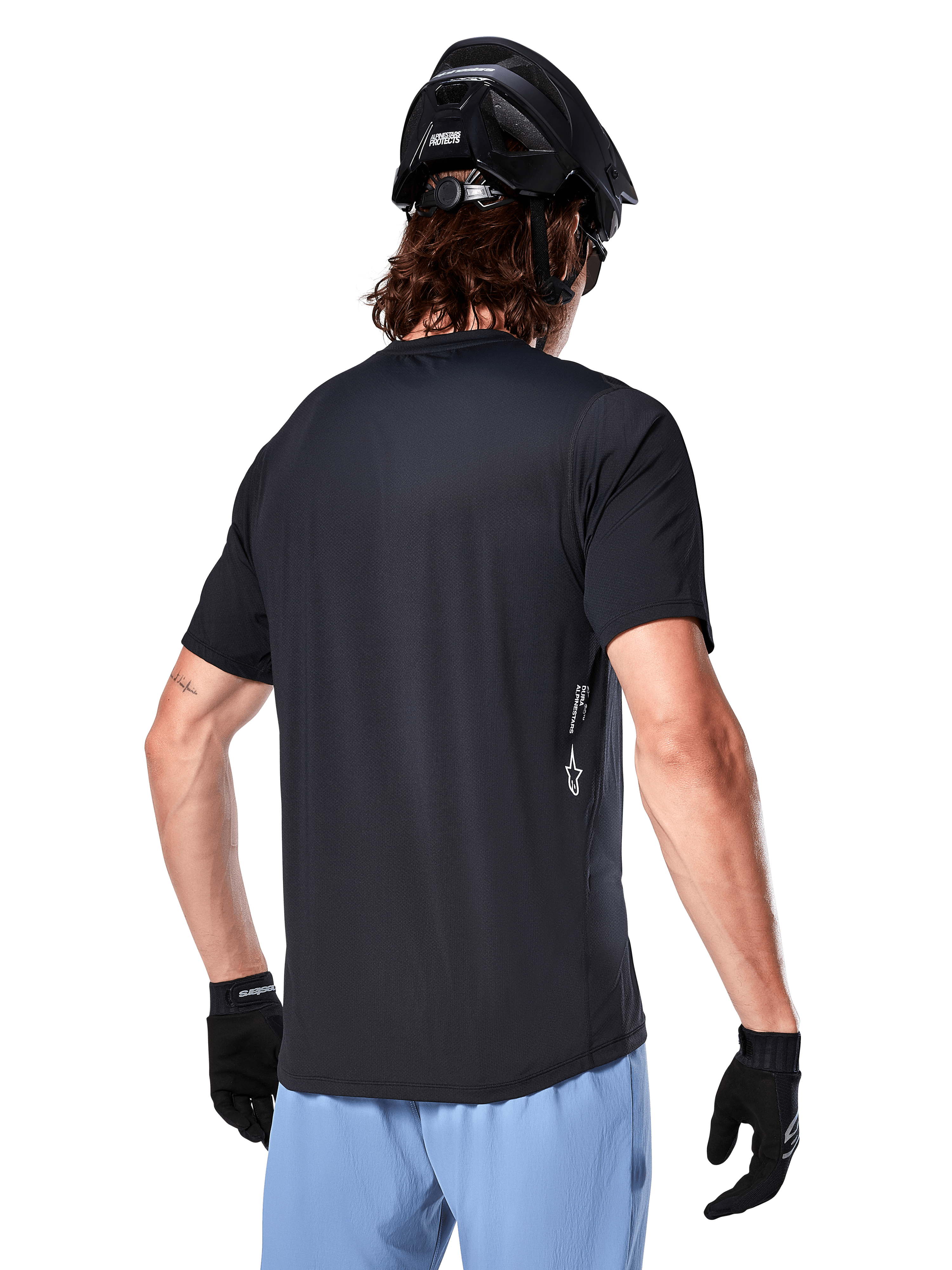 Alpinestars A-Dura Oscar Jersey, maillot de cyclisme à manches courtes, noir, vue de dos sur un cycliste, associé à un short bleu clair et un casque VTT noir, petit logo blanc sur le côté, vêtement de performance pour le VTT