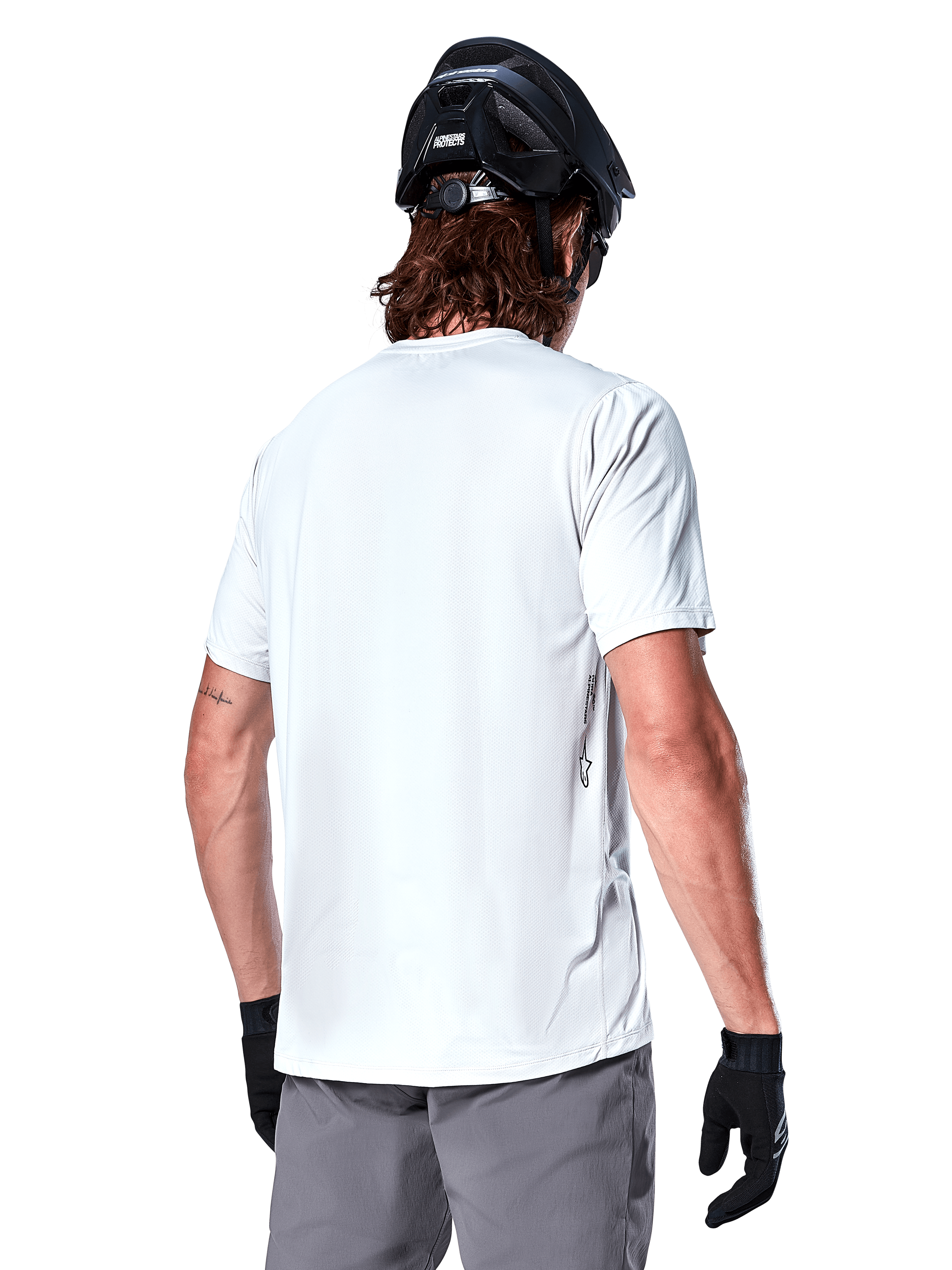 Maillot Alpinestars A-Dura Oscar, maillot de VTT à manches courtes, White Dove, vue de dos d'un cycliste portant un casque de cyclisme noir, un short gris et des gants noirs, équipement de cyclisme technique haute performance