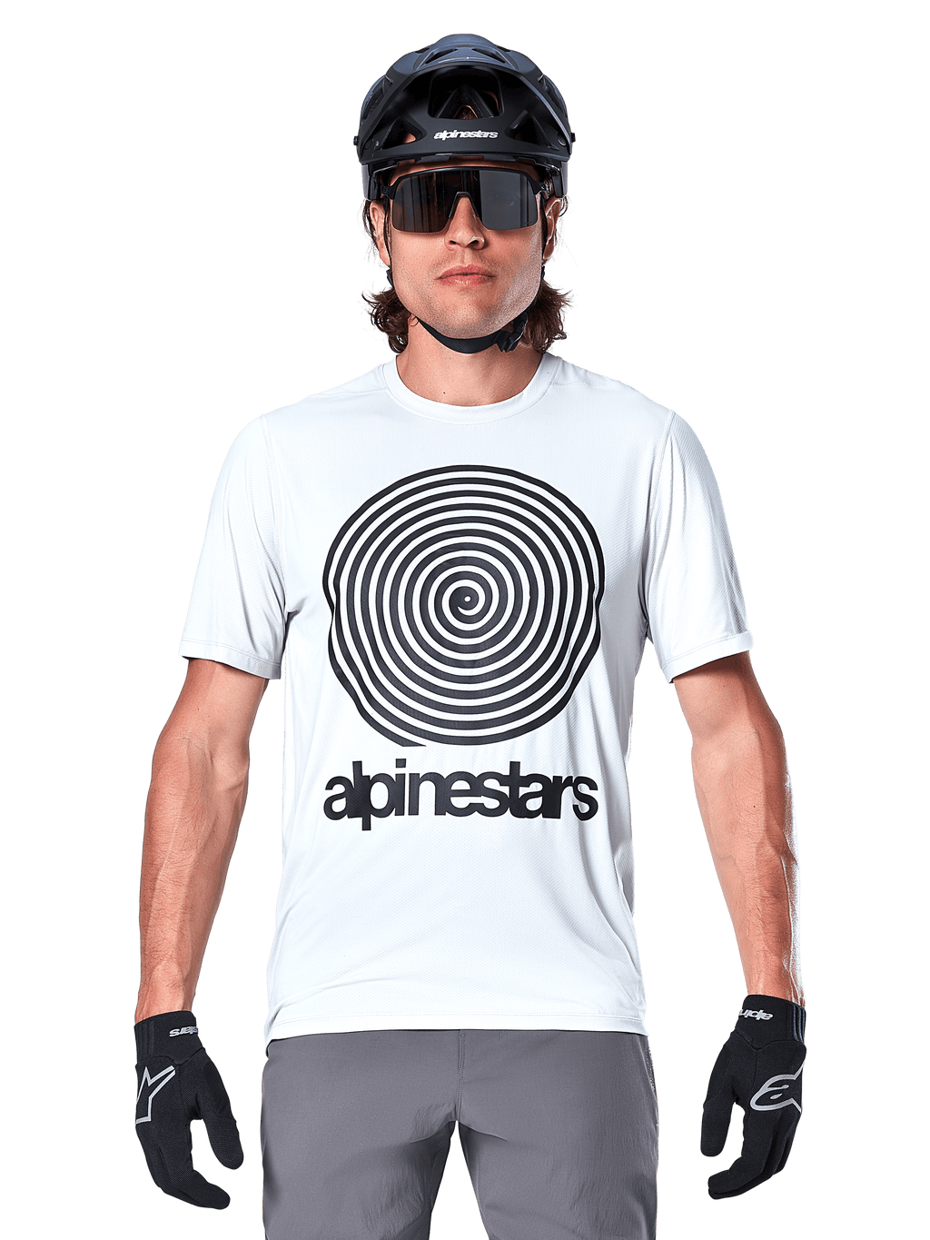 Maillot à manches courtes Alpinestars A-Dura Oscar, White Dove, présentant un grand graphique en spirale Oscar vintage noir et le logotype Alpinestars sur la poitrine, porté par un mannequin avec un casque de VTT noir, des lunettes de soleil et des gants noirs, style cyclisme patrimonial