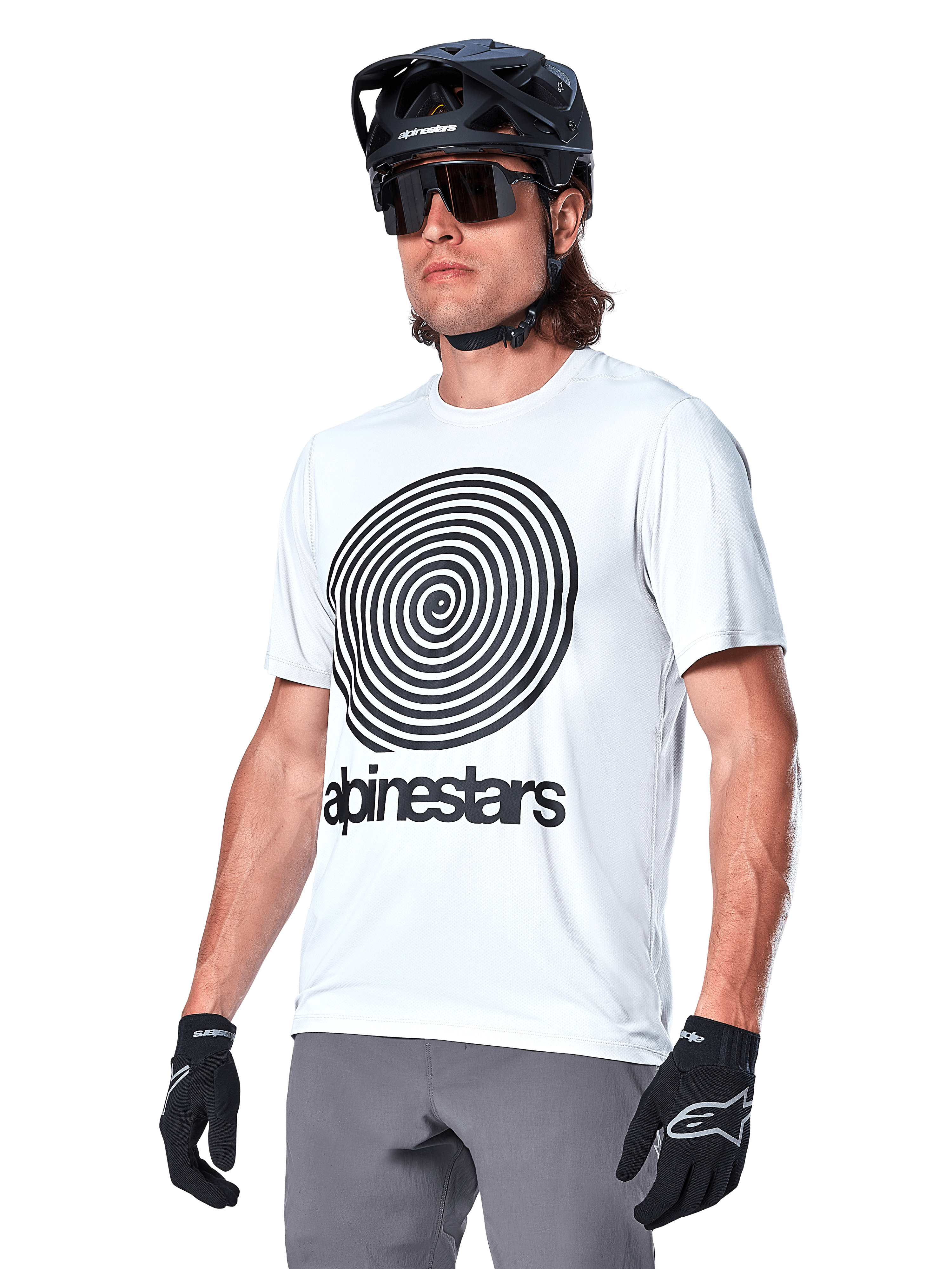 Alpinestars A-Dura Oscar Jersey met korte mouwen, White Dove wit met zwarte heritage spiraalgrafiek en logo, gedragen met zwarte MTB-helm en handschoenen, sportieve performance mountainbikekleding