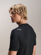 Homme portant le maillot Alpinestars A-Aria Switch à manches courtes, noir, vue latérale et arrière montrant la coupe performance et les détails au niveau de l'épaule, vêtement de VTT léger et respirant