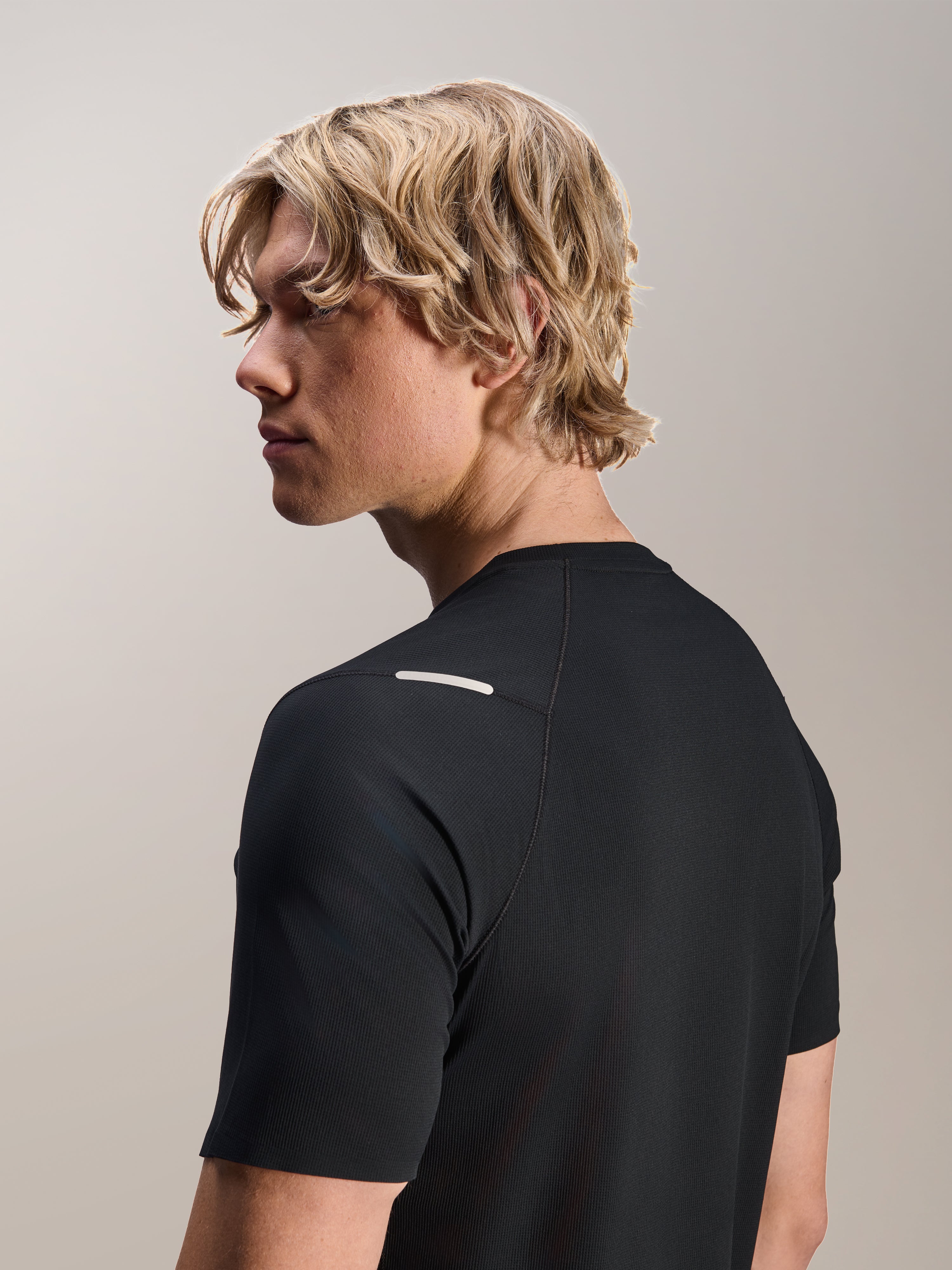 Homme portant le maillot Alpinestars A-Aria Switch à manches courtes, noir, vue latérale et arrière montrant la coupe performance et les détails au niveau de l'épaule, vêtement de VTT léger et respirant