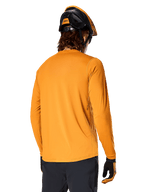 Alpinestars A-Dura Rocker Langarm-Trikot, Dunkelgold, Rückansicht eines Fahrers mit schwarz-orangem MTB-Helm, dunkler Hose und passenden Handschuhen, lässige Performance-Mountainbike-Bekleidung