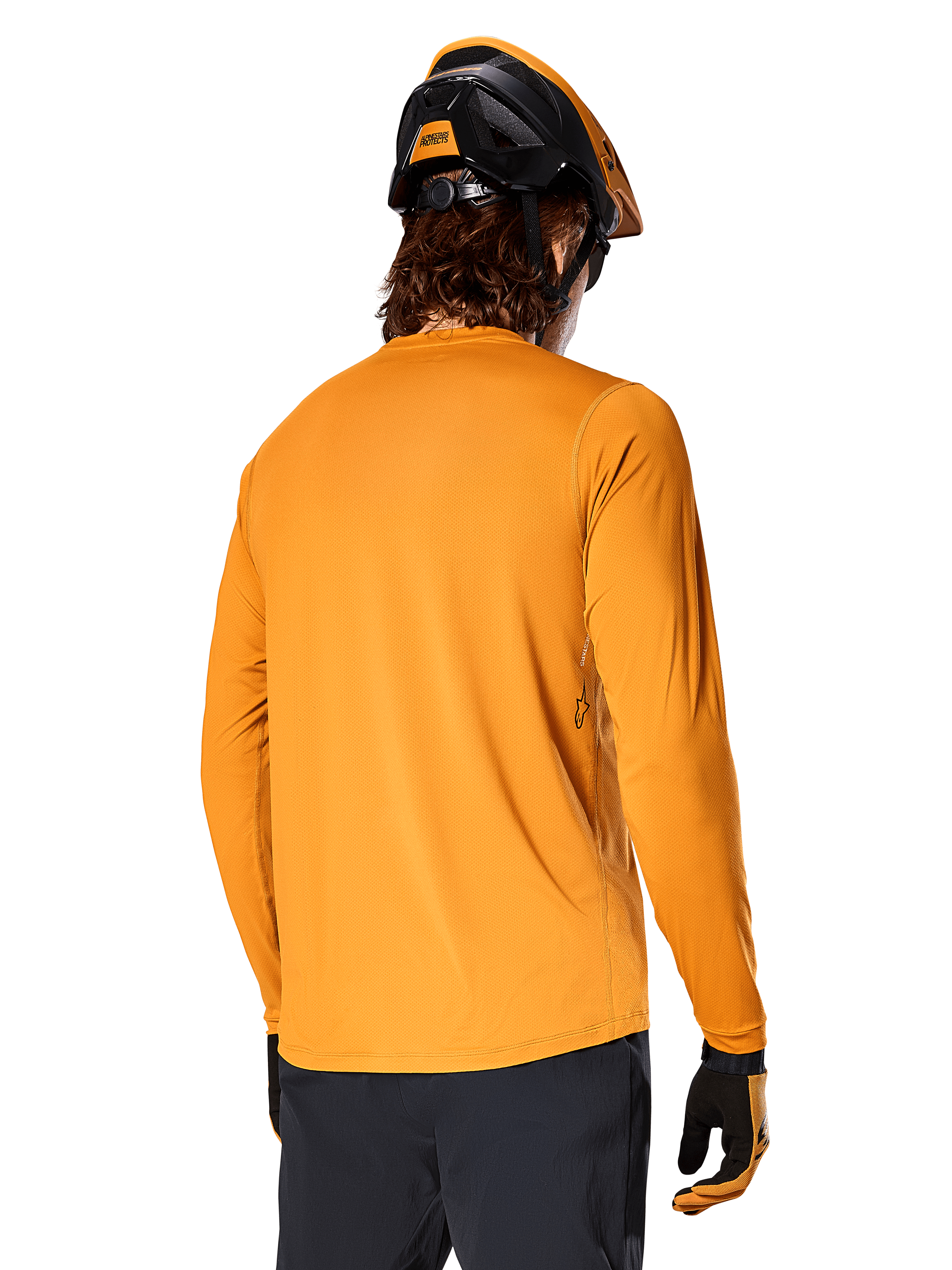 Alpinestars A-Dura Rocker Langarm-Trikot, Dunkelgold, Rückansicht eines Fahrers mit schwarz-orangem MTB-Helm, dunkler Hose und passenden Handschuhen, lässige Performance-Mountainbike-Bekleidung