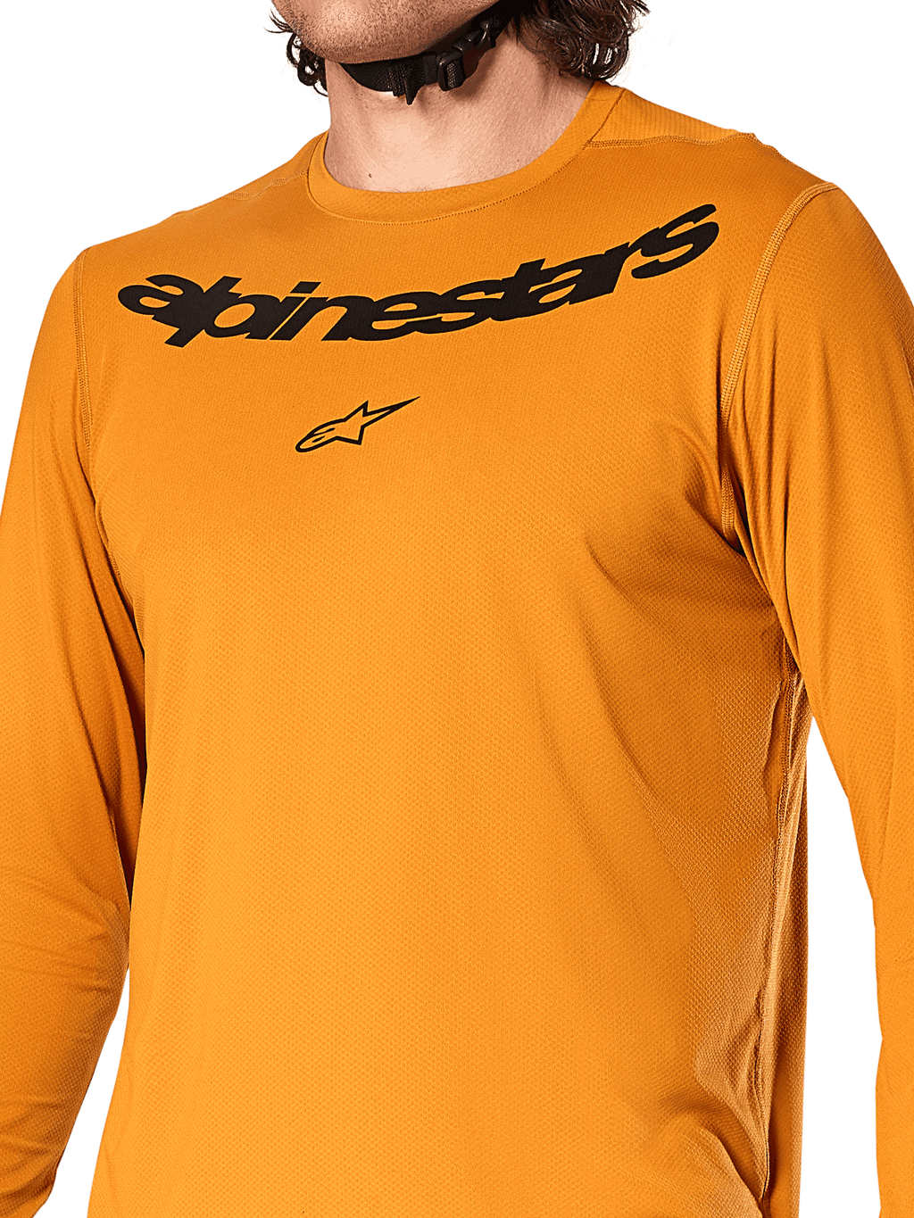 Alpinestars A-Dura Rocker Langarmtrikot, Dunkelgold, Nahaufnahme des Brustbereichs mit schwarzem Alpinestars-Schriftzug und Stern-Logo, strukturiertes feuchtigkeitsableitendes Jacquard-Gewebe, Performance-MTB-Radsportbekleidung