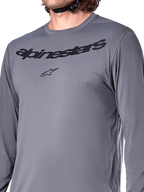 Alpinestars A-Dura Rocker Jersey met lange mouwen, donkergrijs, close-up van de borst met zwart Alpinestars-woordmerk en sterlogo, jacquard poly-spandex materiaal, hoogwaardige mountainbikekleding