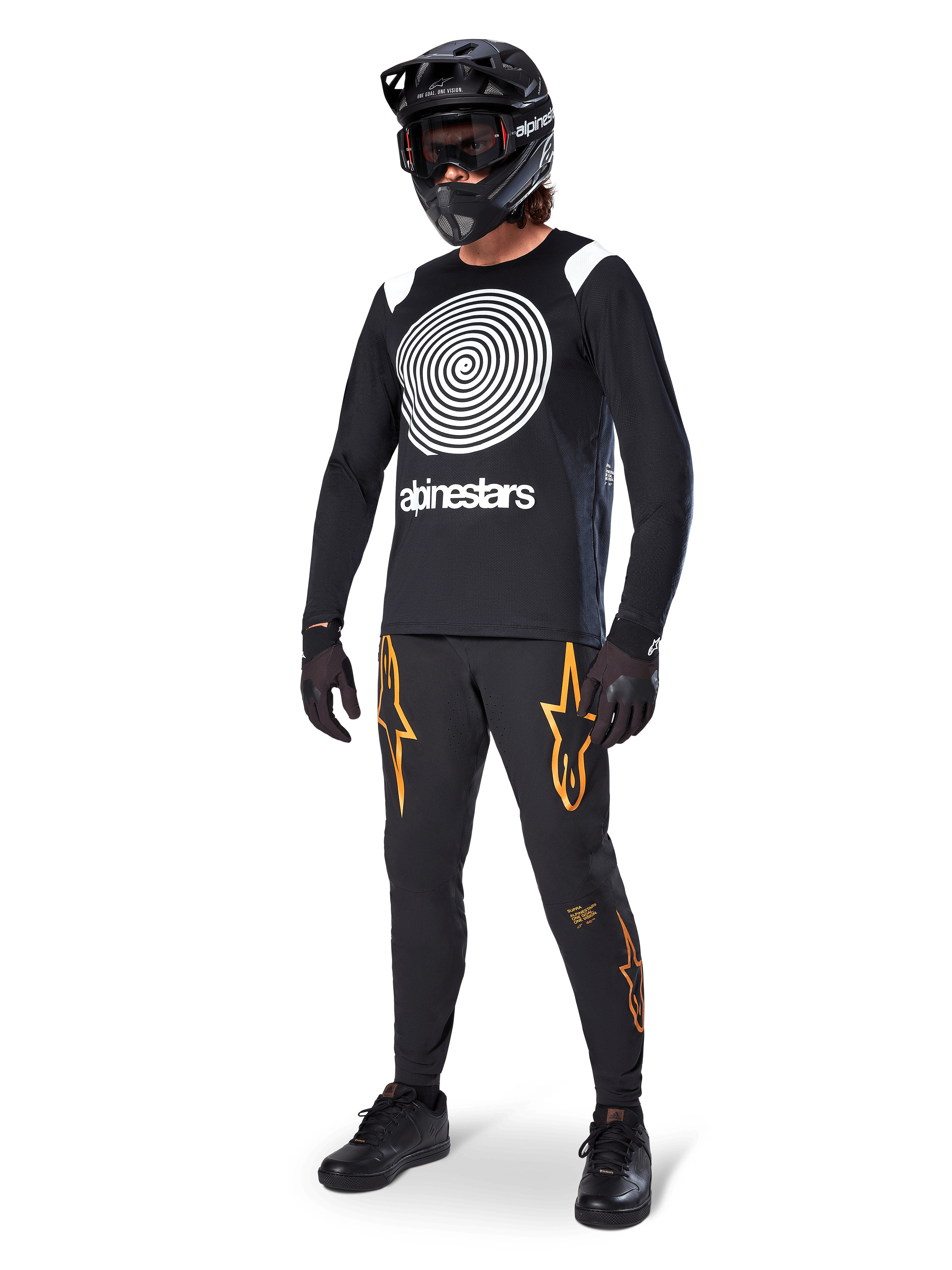 Cycliste de VTT portant le maillot à manches longues Alpinestars A-Supra Oscar noir, graphique en spirale Oscar vintage blanc, pantalon noir avec logos d'étoiles orange, casque intégral noir avec masque et gants noirs, équipement de VTT professionnel