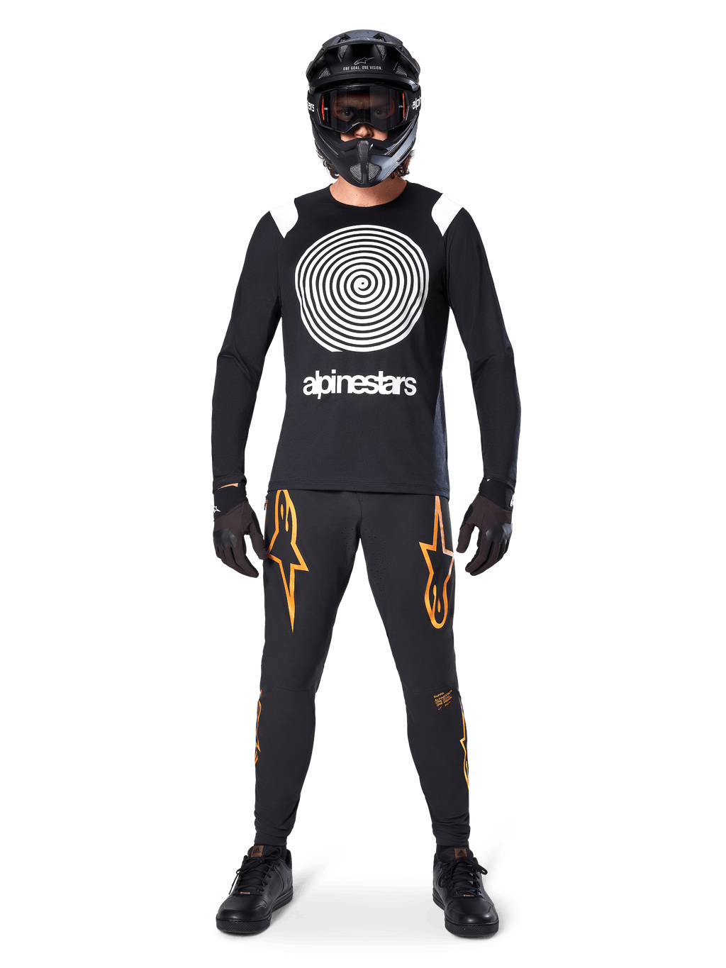 Mannequin homme portant un équipement complet de VTT, maillot à manches longues Alpinestars A-Supra Oscar noir avec graphique en spirale blanc sur la poitrine, pantalon noir avec logos étoiles orange, casque intégral noir et masque, gants et chaussures noirs, tenue coordonnée pour la pratique du VTT en gravité