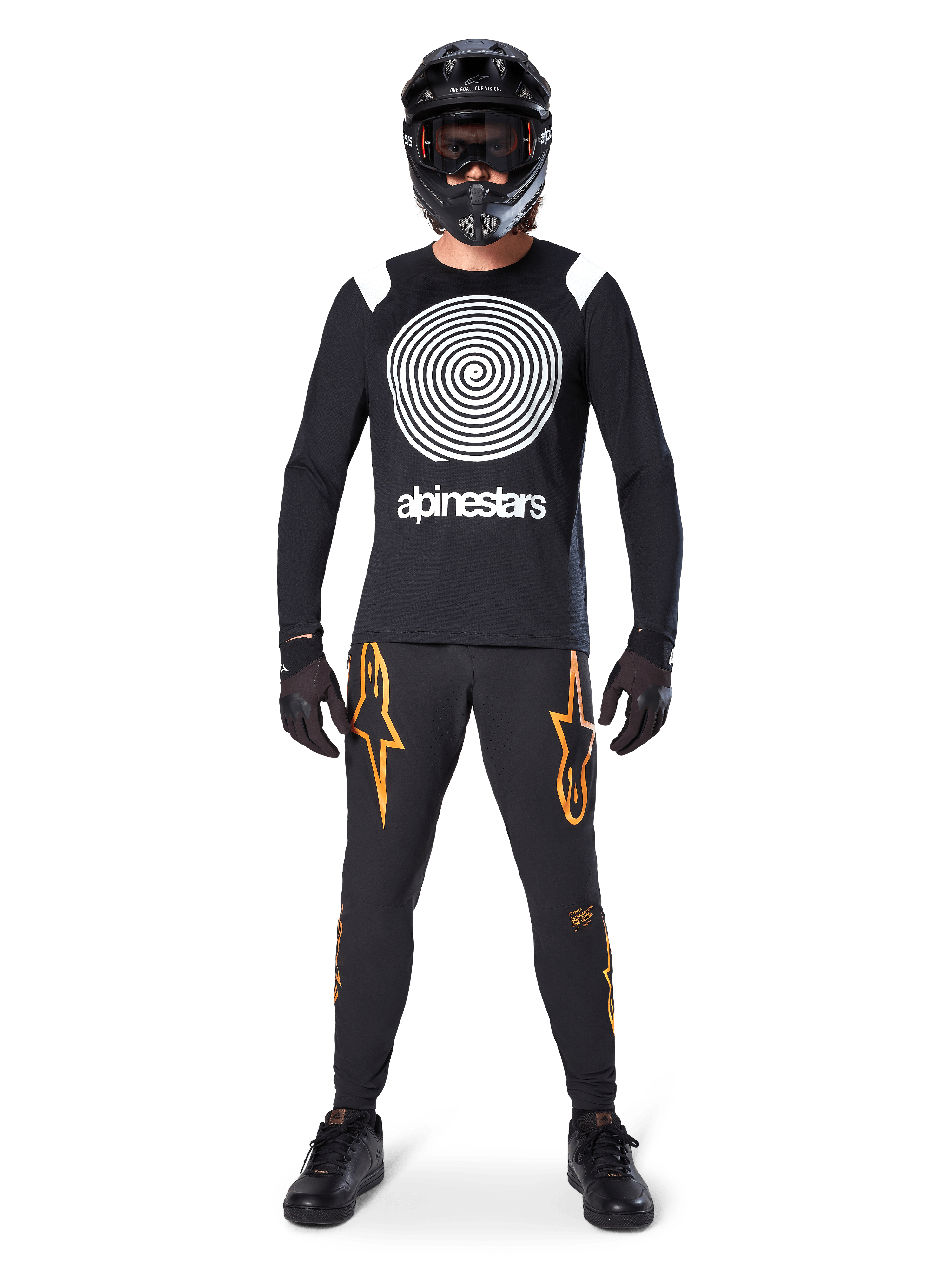 Mannequin homme portant un équipement complet de VTT, maillot à manches longues Alpinestars A-Supra Oscar noir avec graphique en spirale blanc sur la poitrine, pantalon noir avec logos étoiles orange, casque intégral noir et masque, gants et chaussures noirs, tenue coordonnée pour la pratique du VTT en gravité