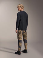 Maillot à manches longues Alpinestars A-Dura Astar, noir, vue de dos sur un mannequin, porté avec un pantalon camouflage, équipement de performance VTT décontracté avec un pan arrière plus long et une coupe régulière