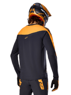 Maillot Alpinestars A-Supra Race - Manches longues, noir et orange, vue arrière d'un pilote portant un casque et un pantalon de VTT assortis, coupe performance avec texture micro-perforée, équipement de course VTT professionnel