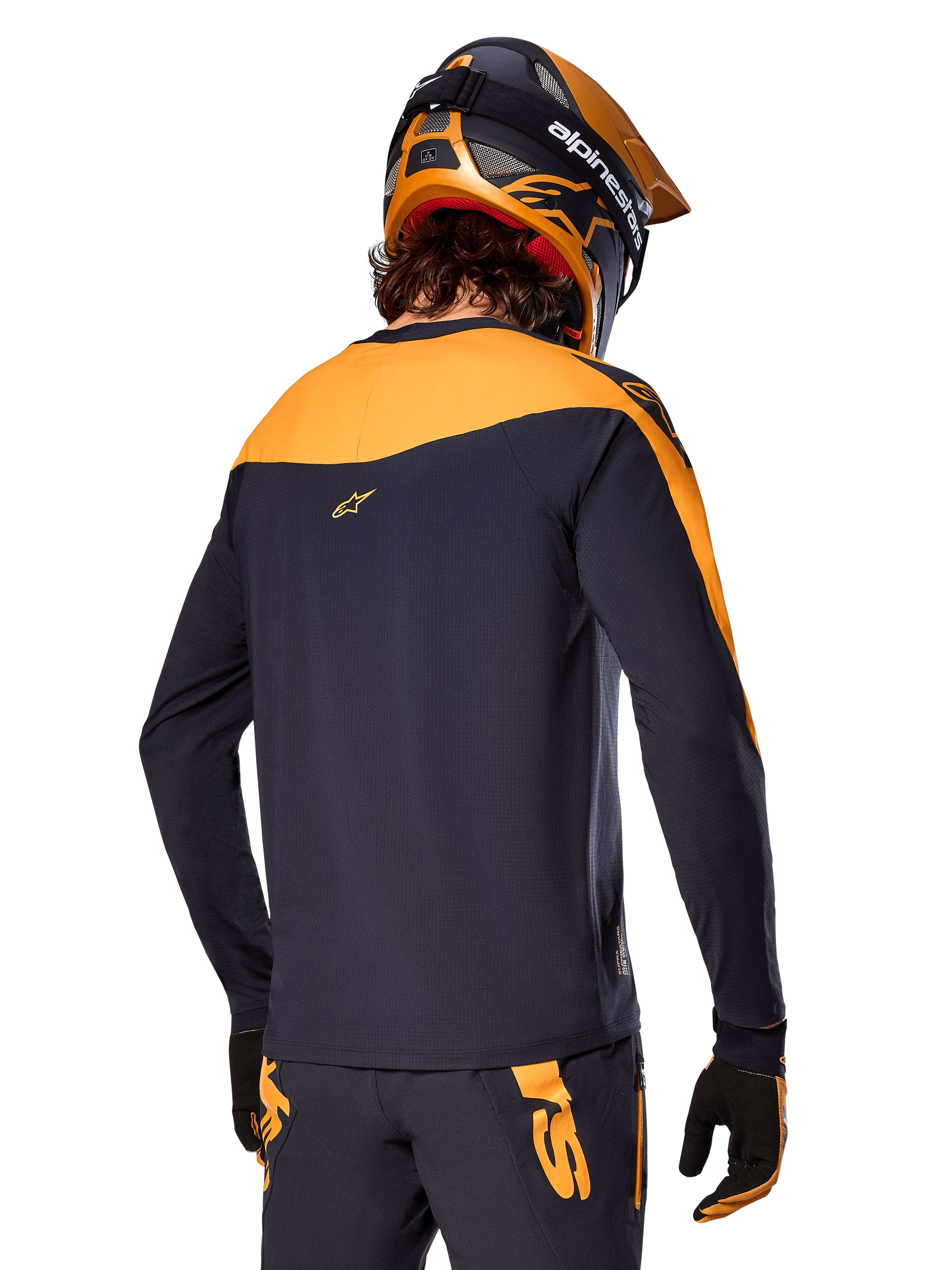 Maillot Alpinestars A-Supra Race - Manches longues, noir et orange, vue arrière d'un pilote portant un casque et un pantalon de VTT assortis, coupe performance avec texture micro-perforée, équipement de course VTT professionnel