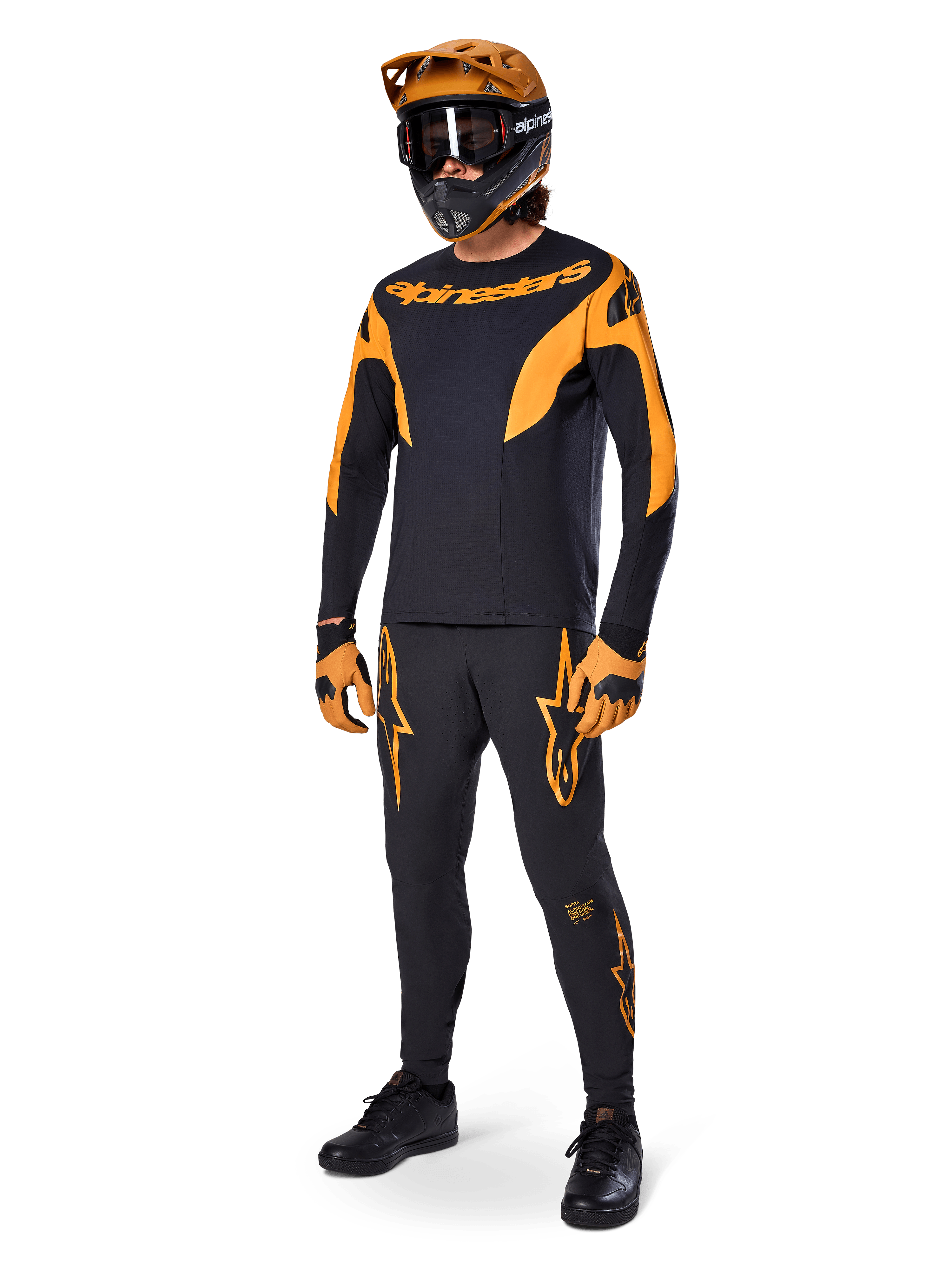 Pilote de VTT en tenue de course complète, maillot A-Supra Race noir avec détails orange, pantalon noir assorti avec logos Alpinestars orange, casque intégral orange et noir avec masque, gants orange et noir, ensemble coordonné pour le VTT de compétition