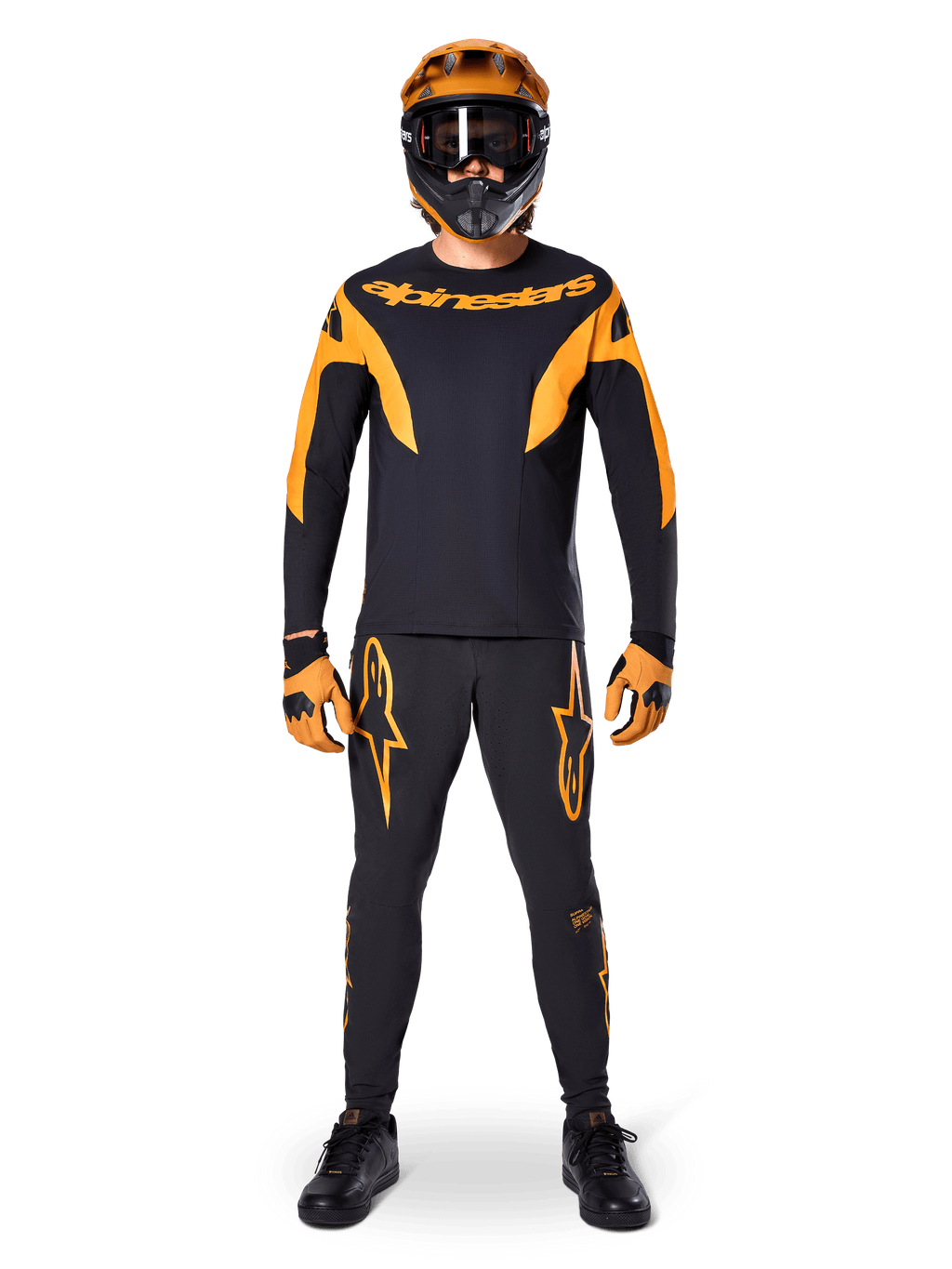 Pilote de VTT portant le maillot Alpinestars A-Supra Race à manches longues noir et orange, pantalon et gants assortis, casque intégral avec lunettes, tenue de VTT coordonnée pour la compétition et la performance tout-terrain