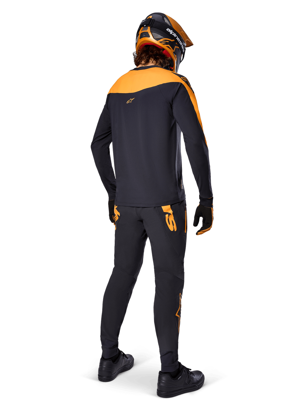 Maillot A-Supra Race - Manches longues, noir et orange, vue arrière d'un pilote portant un pantalon de VTT assorti, un casque orange et noir et des gants, équipement de performance pour la course de VTT
