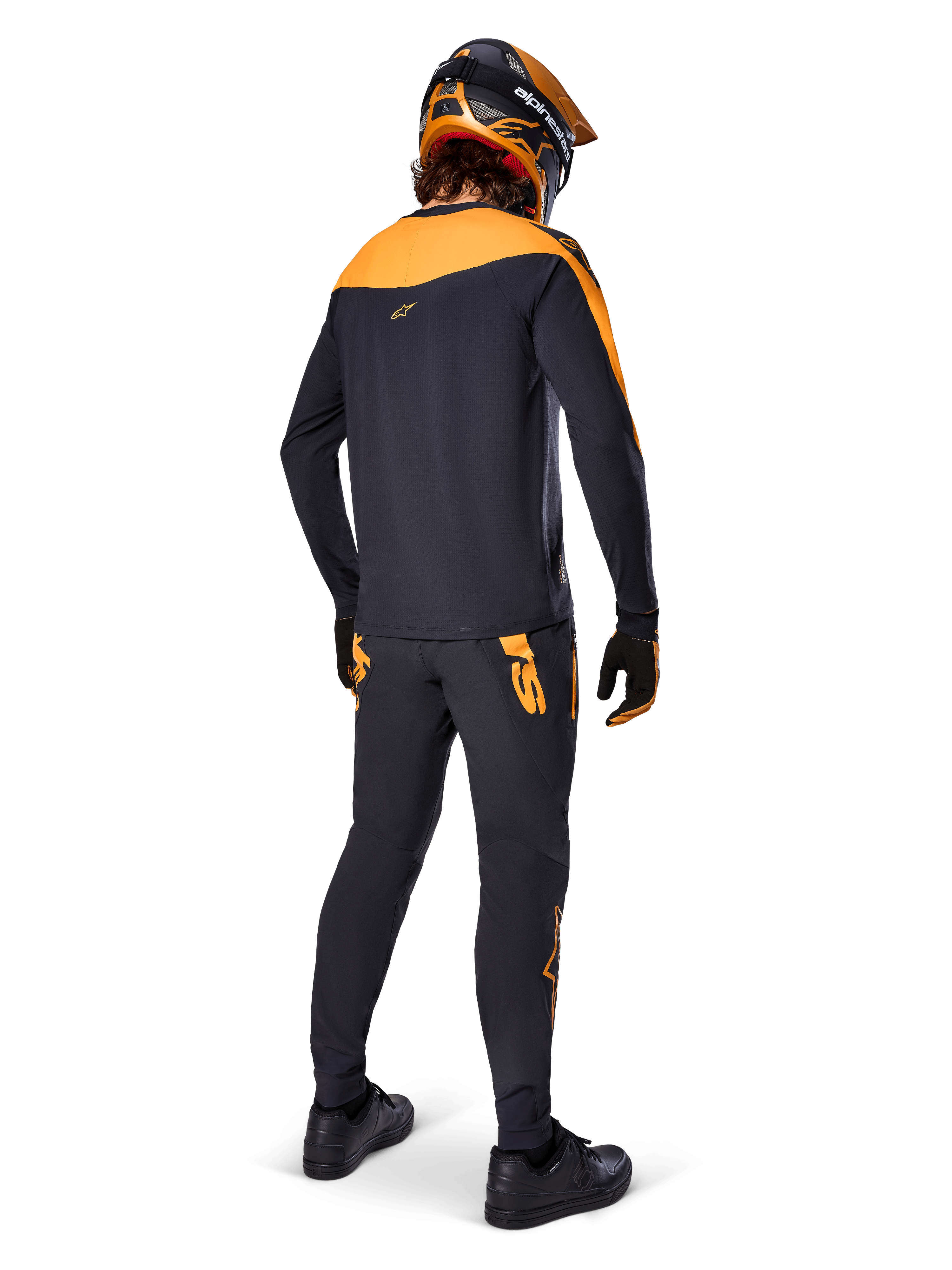 Maillot A-Supra Race - Manches longues, noir et orange, vue arrière d'un pilote portant un pantalon de VTT assorti, un casque orange et noir et des gants, équipement de performance pour la course de VTT