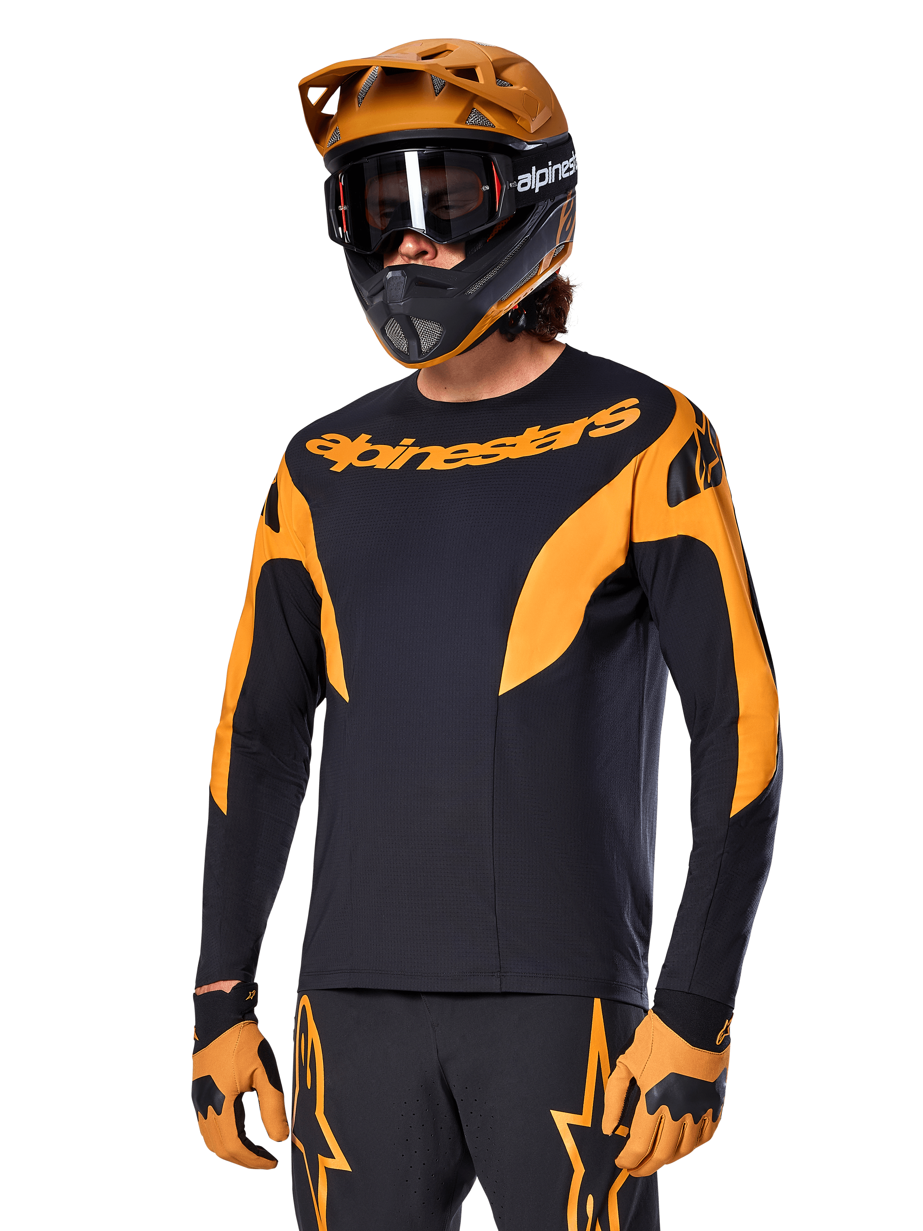 Alpinestars A-Supra Race Jersey à manches longues, maillot de VTT noir et orange, porté avec casque et gants assortis, avec logo Alpinestars sur la poitrine et accents stylisés sur les manches, coupe performance pour la course tout-terrain