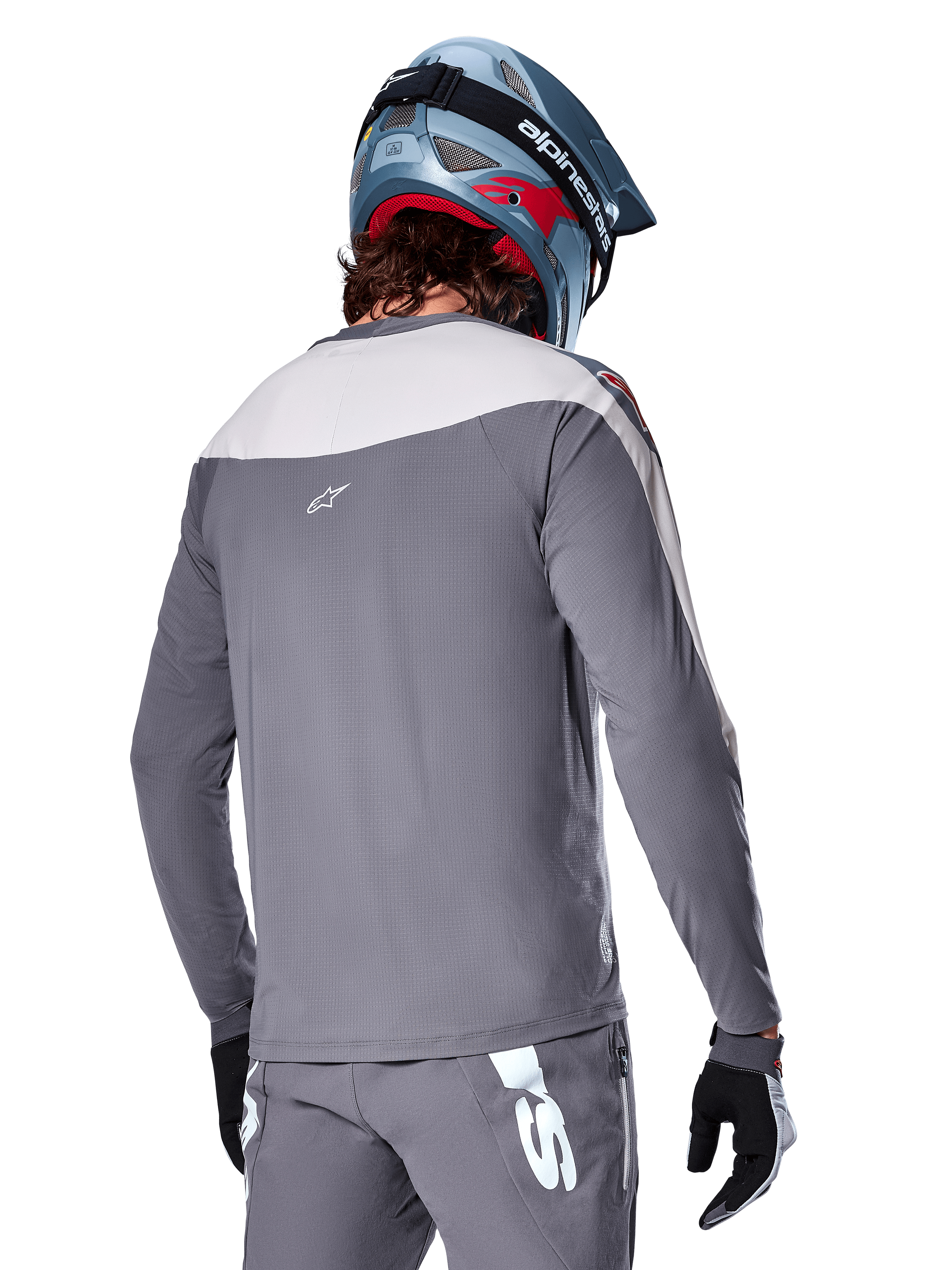 Maillot Alpinestars A-Supra Race, maillot de VTT à manches longues gris foncé et gris clair, vue arrière montrant la coupe performance et le logo Astar, porté avec un pantalon gris assorti et un casque de VTT bleu, conçu pour la pratique du VTT tout-terrain